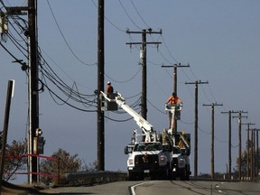 FILE -- Utility crews repair overhead lines along Pacific Coast Highway just west of Malibu, Calif., on Nov. 25, 2018. On Thursday, May 9, 2024, the California Public Utilities Commission will consider a change in how the state's investor-owned utilities calculate their customers' power bills.