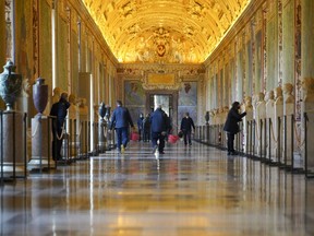 FILE - Museums employees walk down an aisle of the Vatican Museums as they prepare to open the museum, at the Vatican, Monday, Feb. 1, 2021. Forty-nine employees of the Vatican Museums have filed a class-action complaint with the Vatican administration demanding better seniority, leave and overtime benefits in an unusual, public challenge to Pope Francis' governance. The complaint, dated April 23, 2024, was made public the weekend of May 10, 2024, in Italian newspapers.