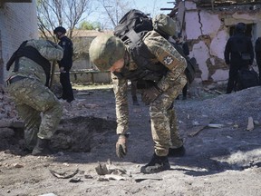 FILE - A police officer examines fragments of a guided bomb after the Russian air raid in Kharkiv, Ukraine, Tuesday, April 30, 2024. Russia pounded a town in Ukraine's northeast with artillery, rockets and guided aerial bombs Friday May 10, 2024 before attempting an infantry breach of local defenses, authorities said, in a tactical switch that Kyiv officials have been expecting for weeks as the war stretches into its third year.