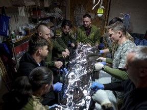 Ukrainian military medics of the 47th Brigade shift an injured comrade to a stretcher at the field hospital in Avdiivka direction, Donetsk region, Ukraine, Friday, May 10, 2024.