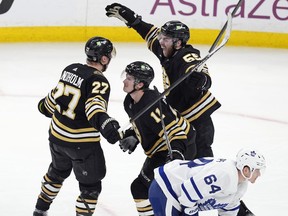 Boston Bruins' Hampus Lindholm (27) celebrates his goal with Justin Brazeau (55) and Trent Frederic (11) behind Toronto Maple Leafs' David Kampf (64) during the third period of Game 7 of an NHL hockey Stanley Cup first-round playoff series, Saturday, May 4, 2024, in Boston.