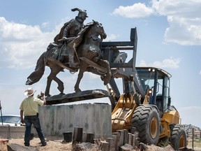 FILE - Rio Arriba County workers remove the bronze statue of Spanish conquerer Juan de Onate from its pedestal in front of a cultural center in Alcalde, N.M., June 15, 2020. A settlement has been reached in a civil lawsuit seeking damages from a 23-year-old man and his parents in the shooting of a Native American activist in northern New Mexico amid confrontations about the statue and aborted plans to reinstall it in public. The settlement was disclosed Tuesday, May 7, 2024, in court documents.