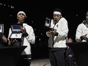 From left, Las Vegas Aces guard Sydney Colson, guard Kierstan Bell and forward Alysha Clark react as they open boxes with their 2023 championship rings before a WNBA basketball game Tuesday, May 14, 2024, in Las Vegas.