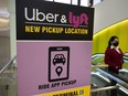 FILE - A passerby walks past a sign offering directions to an Uber and Lyft ride pickup location at an airport, Feb. 9, 2021.