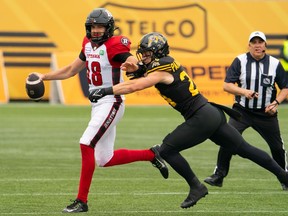 Ottawa Redblacks quarterback Dustin Crum (18) fends off Hamilton Tiger Cats defensive back Robert Panabaker (24) during CFL pre-season football game action in Hamilton, Ont. on Saturday, May 25, 2024.