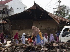 People inspect the damage by a flash flood in Tanah Datar, West Sumatra, Indonesia, Wednesday, May 15, 2024. Indonesian authorities seeded clouds on Wednesday, trying to prevent further rain and flash floods after deluges that hit the country's Sumatra Island over the weekend left a number of people dead and missing.