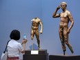 FILE - Reporter Sookee Chung takes a photo of a sculpture titled "Statue of a Victorious Youth, 300-100 B.C." at the J. Paul Getty Museum in Los Angeles, on July 27, 2015. A European court upheld Italy's right to seize a prized Greek statue from the J. Paul Getty Museum in California, rejecting the museum's appeal on Thursday and ruling Italy was right to try to reclaim an important part of its cultural heritage.