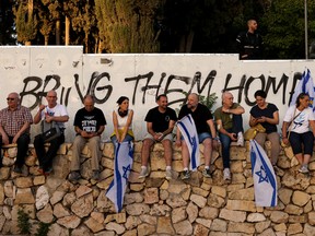 Israelis sit in front of graffiti
