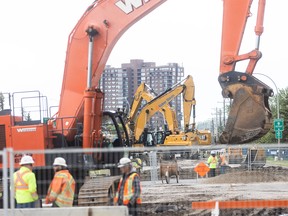 Excavators operate over multiple pits on 16 Avenue N.W. in Calgary.