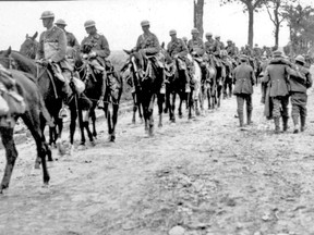 Canadian soldiers ride by wounded Germans.