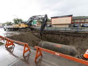 An excavator works around a length of exposed water feeder main on 16 Avenue N.W. between 45 and 46 Streets in Calgary on Tuesday, June 18, 2024. The segment is one of five weak points identified in the water pipeline following a major break earlier this month.