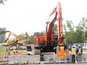 Excavators operate over multiple pits on 16 Avenue N.W. east of 43 Street in Calgary on Tuesday, June 18, 2024 to repair a segment of a damaged water feeder main.