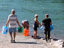 Calgarians collect their own water from the Bow river on Sunday.