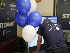 A Conservative supporters watches a split screen displaying voting results and the Stanley Cup final, at an Federal byelection election night event for Toronto-St.Paul's candidate Don Stewart in Toronto on Monday, June 24, 2024.THE CANADIAN PRESS/Chris Young