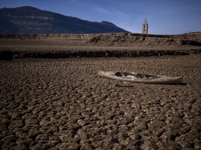 FILE - An abandoned canoe sits on the cracked ground amid a drought at the Sau reservoir, north of Barcelona, Spain, Monday, Jan. 22, 2024. A top United Nations official says even though climate change makes disasters such as cyclones, floods and droughts more intense, more frequent and striking more places, fewer people are dying from those catastrophes globally. Thats because of better warning, planning and resilience.