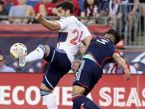 Vancouver Whitecaps forward Brian White (24) defends the ball from New England Revolution defender Xavier Arreaga (3) during the first half of an MLS soccer match Saturday, June 15, 2024, in Foxborough, Mass.