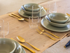 table setting with green ceramic dishes and gold cutlery