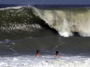 FILE - Shaun Clark, left, and Jim Donnelly watch as a big wave starts to come ashore at Fernandina Beach, in Nassau County, Fla., Sept. 16, 2003. A man on Florida's east coast was bitten by a shark this weekend, but is now recovering, Nassau County authorities said Sunday, June 30, 2024, in the third shark attack in state waters over the past month.