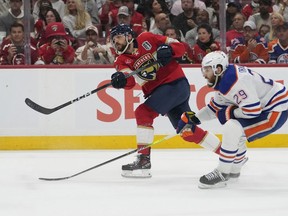 Florida Panthers center Sam Reinhart, left, aims the puck for a goal as Edmonton Oilers center Leon Draisaitl (29) attempts to defend during the second period of Game 7 of the NHL hockey Stanley Cup Final, Monday, June 24, 2024, in Sunrise, Fla.