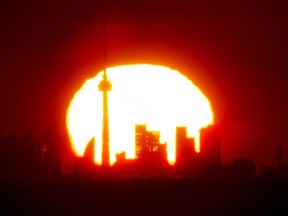 A new report by Statistics Canada says deaths in the country's 12 highest-population cities go up on days when there is extreme heat. The sun rises over the Toronto skyline on Saturday, May 1, 2021.