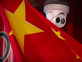 A Chinese flag hangs near a Hikvision security camera outside of a shop in Beijing, Tuesday, Oct. 8, 2019.