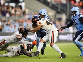 Toronto Argonauts running back Ka'Deem Carey (25) is stopped by B.C. Lions defensive back Emmanuel Rugamba (33), defensive back Garry Peters (1) and defensive lineman Pete Robertson (40) while Argonauts offensive lineman Dejon Allen (59) moves toward the play, during first half CFL action, in Toronto, on June 9, 2024.