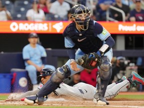 Cleveland Guardians' Brayan Rocchio (4) slides into home safely as Toronto Blue Jays catcher Danny Jansen (9) plays the ball during fifth inning MLB baseball action in Toronto on Friday, June 14, 2024.