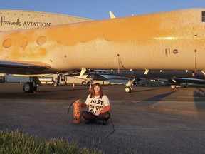 An activist poses next to private airplane sprayed with orange paint at the Stansted Airport, Britain
