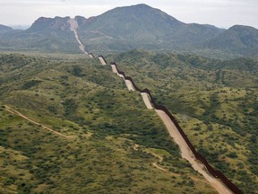FILE - The border between the United States and Mexico, at right, cuts through the Sonoran Desert at the base of the Baboquivari Mountains, Thursday, Sept. 8, 2022, near Sasabe, Ariz. The bodies of three Mexican migrants have brern found Wednesday, June 27, 2024, in the Sonoran Desert near the Arizona-Mexico border as temperatures hit the triple digits across parts of the Southwest.