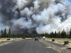 Smoke from a wildfire rises on a road near La Pine, Ore., Tuesday, June 25, 2024. The fire prompted mandatory evacuations in the small town in central Oregon and was growing rapidly in hot, dry conditions.