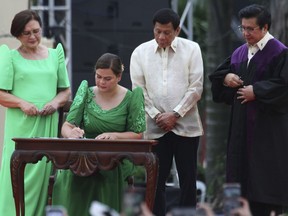FILE - Sara Duterte, daughter of outgoing populist president of the Philippines, signs documents during her oath taking as vice president in her hometown in Davao city, southern Philippines, Sunday, June 19, 2022. Philippine Vice President Sara Duterte resigned Wednesday, June 19, 2024, from President Ferdinand Marcos Jr.'s Cabinet in the latest sign that their whirlwind political alliance has unraveled over key differences, including government efforts to arrest a religious leader accused of sex abuses and Manila's handling of its escalating territorial disputes with Beijing.