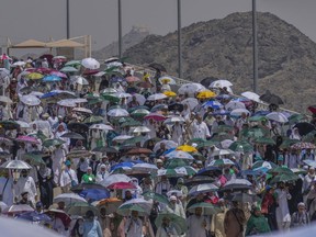 Muslim pilgrims use umbrellas to shield themselves from the sun as they arrive to cast stones at pillars in the symbolic stoning of the devil, the last rite of the annual hajj, in Mina, near the holy city of Mecca, Saudi Arabia, Tuesday, June 18, 2024.