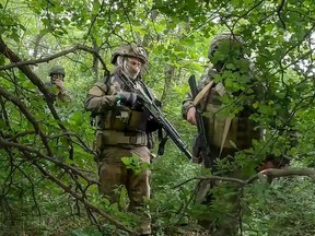 FILE - In this photo, taken from video released by the Russian Defense Ministry Press Service on Wednesday, June 12, 2024, Russian soldiers walk through a forest in an undisclosed location in Ukraine. Russia has taken advantage of its edge in firepower amid delays in U.S. aid to scale up attacks in several areas along the 1,000-kilometer (600-mile) front. (Russian Defense Ministry Press Service via AP, File)