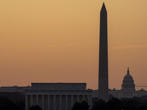 The sky glows orange as the sun rises near the U.S. Capitol, Washington Monument and Lincoln Memorial in Washington, Friday, June 21, 2024, as seen from Arlington, Va. The National Weather Service said scorching temperatures will linger across the Ohio Valley and Mid-Atlantic region.