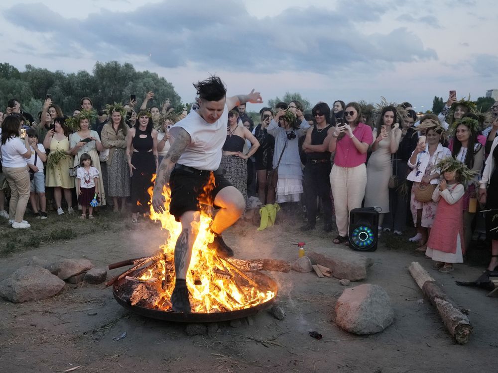 A Ukrainian man jumps over fire during a traditional Ukrainian celebration of Kupalo Night, in Warsaw, Poland, on Saturday, June 22, 2024. Ukrainians in Warsaw jumped over a bonfire and floated braids to honor the vital powers of water and fire on the Vistula River bank Saturday night, as they celebrated their solstice tradition of Ivan Kupalo Night away from war-torn home.