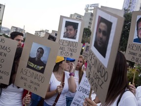 FILE - Demonstrators holds cardboard posters showing images of family and friends killed during anti-government protests, in Caracas, Venezuela, March 18, 2014. An Argentine federal court in Buenos Aires on June 28, 2024, concluded testimony from Venezuelan victims as part of an investigation into probable human rights abuses allegedly committed by security forces during the 2014 clampdown on mass anti-government protests.