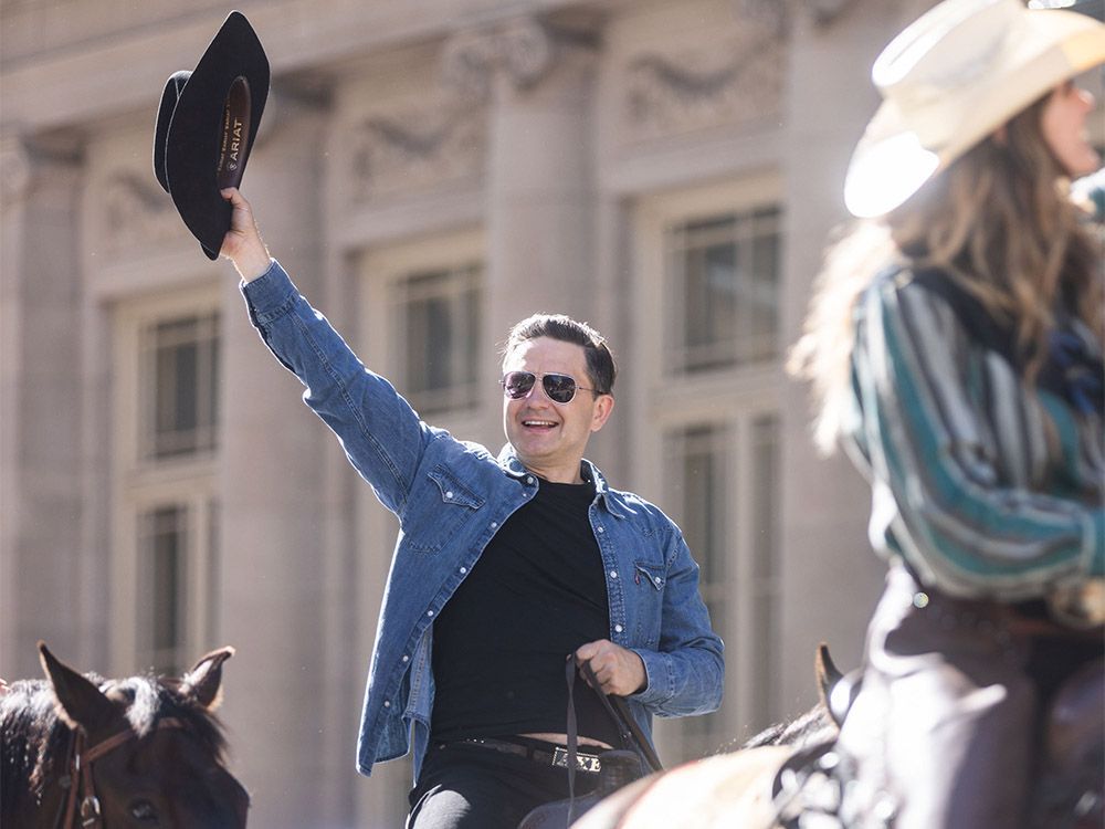 Pierre Poilievre waves while riding horseback in the Calgary Stampede Parade on Friday.