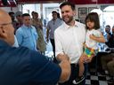 Republican vice-presidential nominee J.D. Vance carries his daughter Maribel as he arrives to greet supporters at a diner in St. Cloud, Minn., on July 28, 2024.