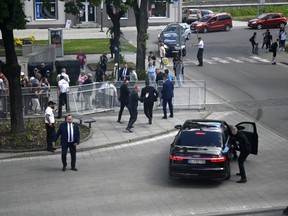 FILE - Bodyguards take Slovak Prime Minister Robert Fico in a car from the scene after he was shot and injured following the cabinet's away-from-home session in the town of Handlova, Slovakia, on May 15, 2024. Slovakia's authorities started to investigate a suspect in an attempted assassination on populist Prime Minister Robert Fico as a terror attack, the country's prosecutor general said on Thursday, July 4, 2024.