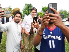 Prime Minister Justin Trudeau, centre, takes selfies with people as they greet him in a park in his Papineau riding in Montreal, Wednesday, July 3, 2024.