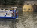 A ship sails past reproductions of artworks decorating the banks of the River Seineat the 2024 Summer Olympics, Tuesday, July 30, 2024, in Paris, France.