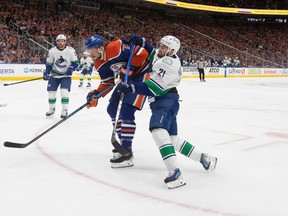 Vancouver Canucks' Nils Hoglander (21) is checked by Edmonton Oilers' Vincent Desharnais (73) during NHL playoff action in Edmonton on Saturday May 18, 2024.
