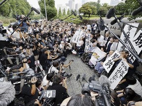 The plaintiffs, their lawyers and supporters hold the signs reading "Winning lawsuit" outside the Supreme Court after in Tokyo, Japan, Wednesday, July 3, 2024. Japan's Supreme Court, in a landmark decision Wednesday, ordered the government to pay compensation to dozens of victims who were forcibly sterilized in the 1950s to 1970s under a now-defunct Eugenics Protection Law that was designed to eliminate offsprings of people with handicaps. (Kyodo News via AP)