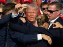 Republican candidate Donald Trump is seen with blood on his face surrounded by secret service agents as he is taken off the stage at a campaign event at Butler Farm Show Inc. in Butler, Pennsylvania, July 13, 2024.