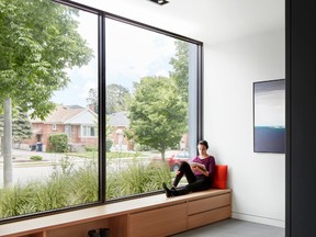 Wide-open glazing brightens the front vestibule and frames a leafy street view, while closets lining the inside wall maintain privacy for areas further inside.