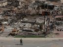 A worker walks in a devastated neighbourhood in west Jasper, Alberta on Monday August 19, 2024.