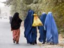 Burqa-clad women walk along a street on the outskirts of Kandahar, Afghanistan, on October 15, 2024.