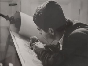 A young man writes onto parchment.