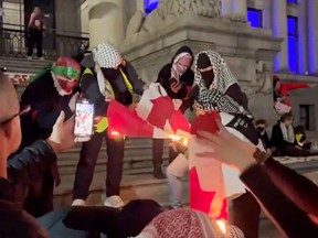 A group of people burn a Canadian flag.