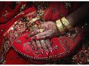 A Pakistani bride folds her hands decorated with henna and jewellery at her wedding party.